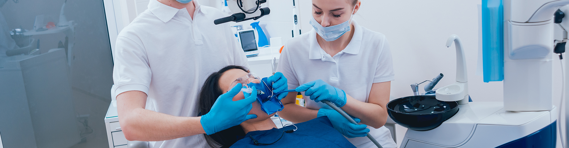 dental staff working in the mouth of patient in dental chair